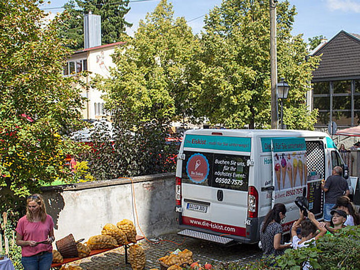 Dorfladen mit Transporter und Personen davor