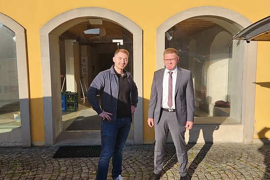 Zwei Personen stehen vor dem Gebäude des Dorfladens.